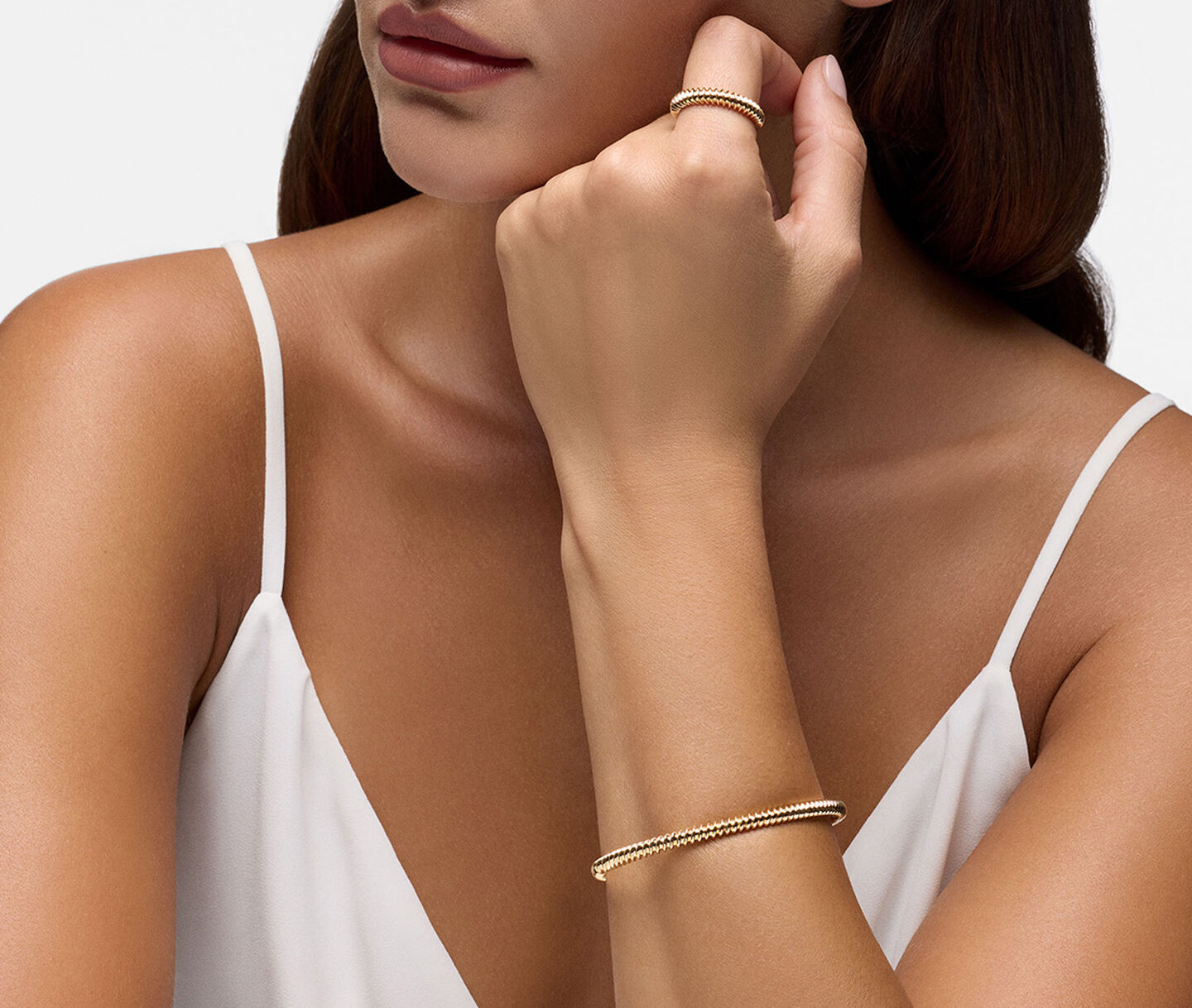 A woman wearing a Birks Essentials yellow gold bracelet and ring.